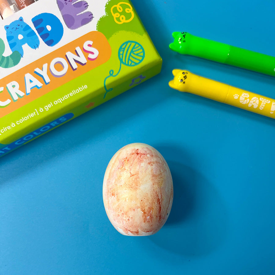 The faux egg now fully blended with a soft, pastel-like watercolor effect. The OOLY Cat Parade Gel Crayons are placed beside it. Step 4.