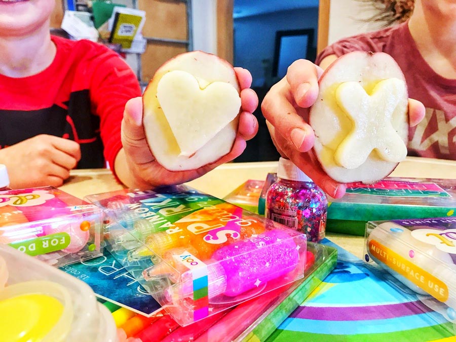 Kids holding heart and X potato stamps for Valentine's DIY stamping