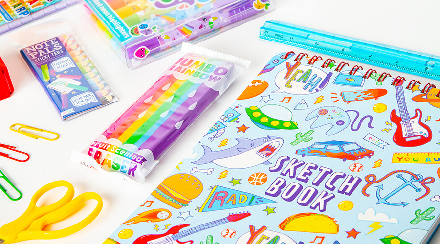 sketch book with colorful school supplies on white surface