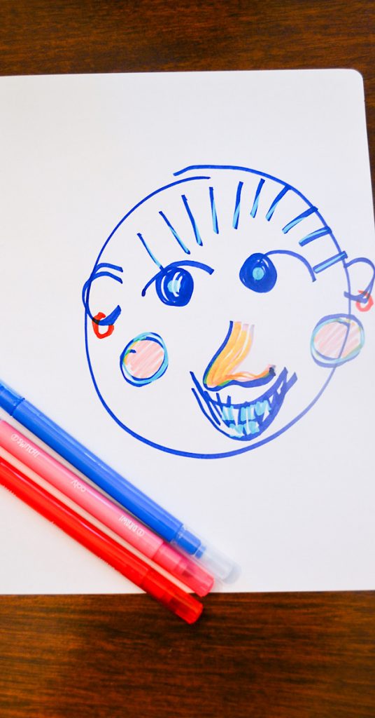 blue smiling face on white paper on wooden surface