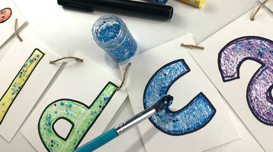 letters colored in with blue glitter being added with blue paint brush