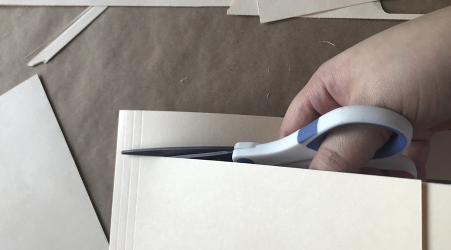 hand holding scissors cutting manila envelope