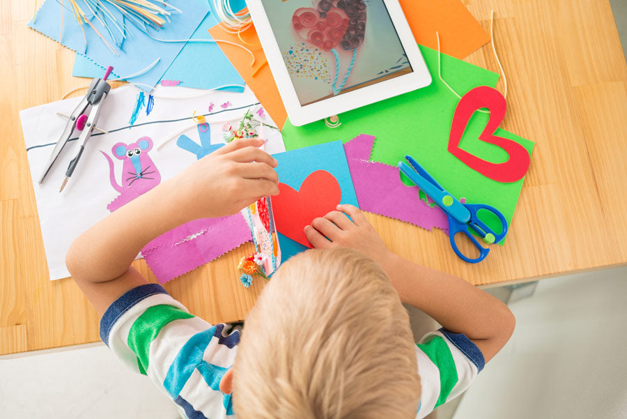 Boy with colorful construction paper, ready to make handmade cards