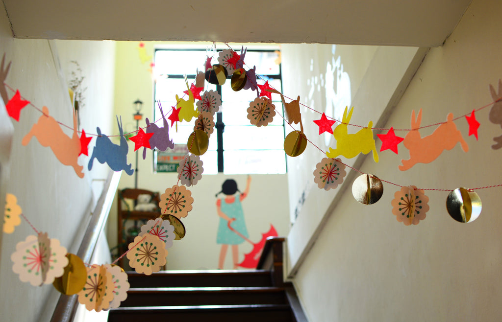 Paper animal garland and golden discs hanging in a stairway