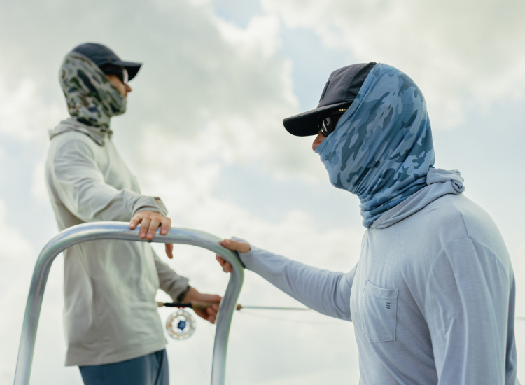 Men fishing while wearing sun masks and hoodies