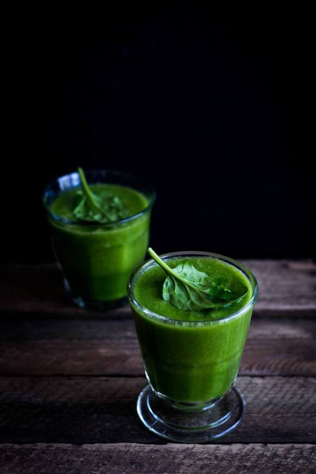 two glasses of green vegetable smoothies on wooden table