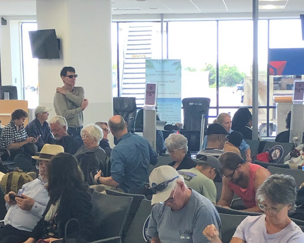 crowded airport waiting area with massage chairs