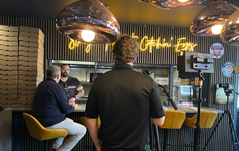 interior of Hudson & Packard pizzeria with film crew and men talking