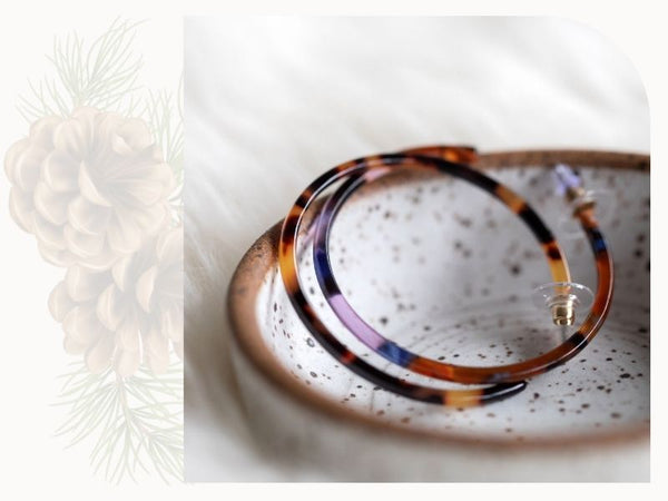 A pair of resin hoops are shown in a ceramic bowl. They are multicoloured.