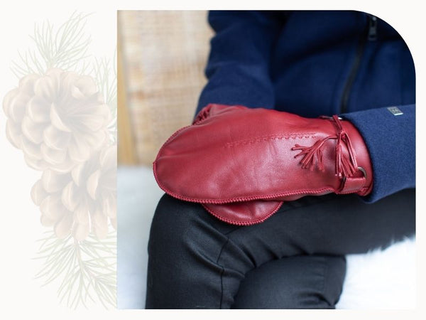 A woman wears a pair of red leather mitts with tassels at the wrist.