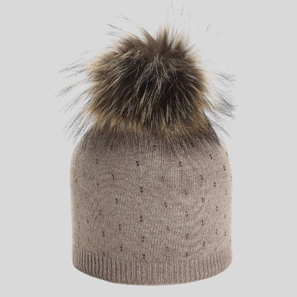 A beige hat is shown, with tiny rhinestones on the body of the hat, and a fur pompom on top.