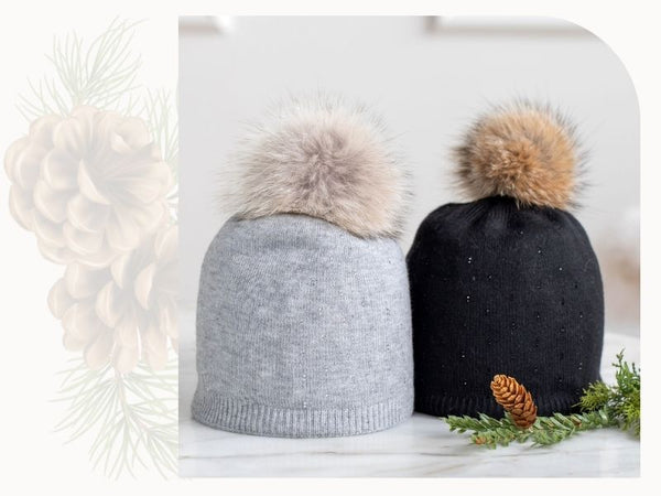 Two hats with pompoms are shown. One is a soft gray and the other is black. The pompoms are natural fur.