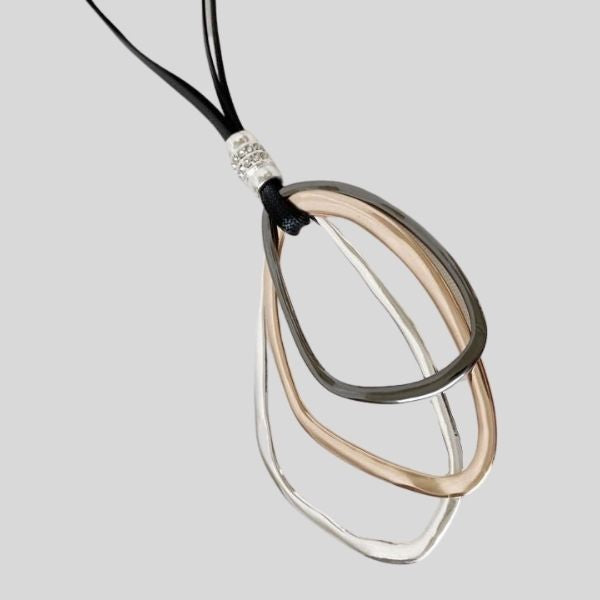 A pendant is shown. Three metal loops of irregular shape hangs from a black leather thong.