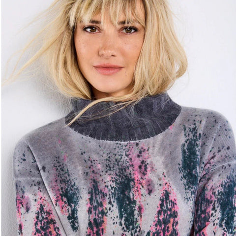 A woman is shown wearing a multicoloured turtleneck sweater. It's made of cashmere.