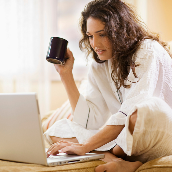 A woman is shown typing on a laptop and holding a coffee mug.