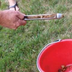 Soil probe with a sample of soil and a red bucket