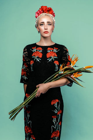 Model holds strelitzia flowers in Frida Kahlo costume dress wears monstera stud earrings for the Katmeleon Jewellery Frida Kahlo Collection