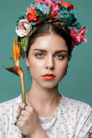 Model wears the Katmeleon Jewellery Chameleon Silver Ring and Monstera Stud Earrings while holding a strelitzia
