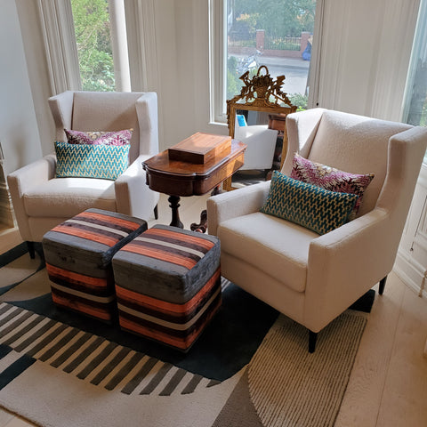 Paired beige armchairs with striped throw pillows by Kendall & Co.