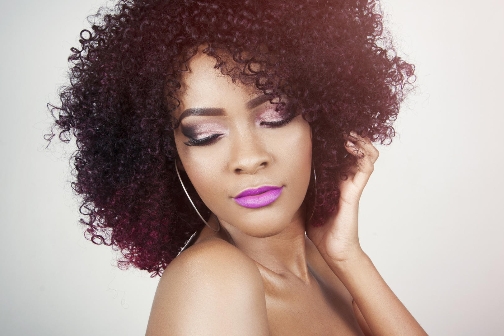 A beautiful black woman holding her rich brown curly locks.