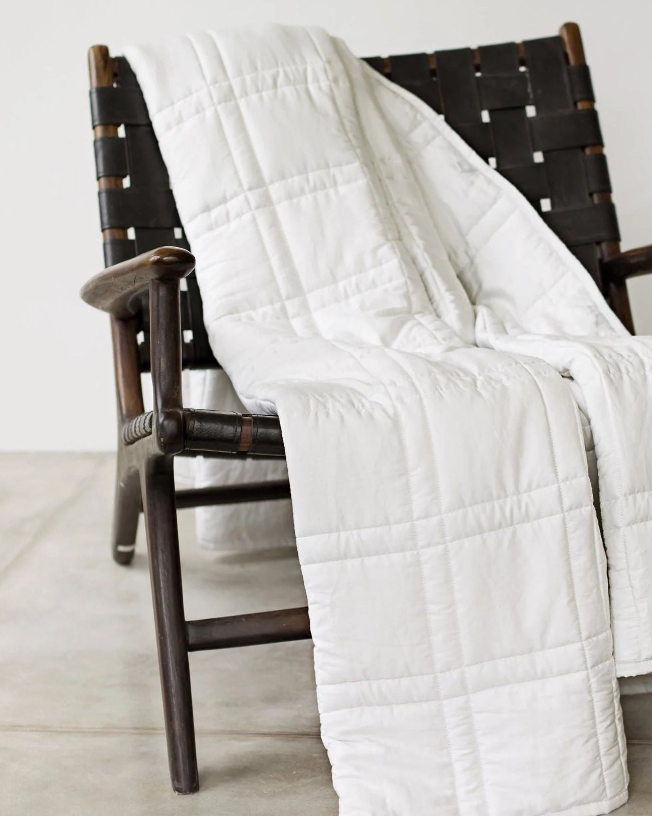 A white Baloo Weighted Blanket draped in a chair.