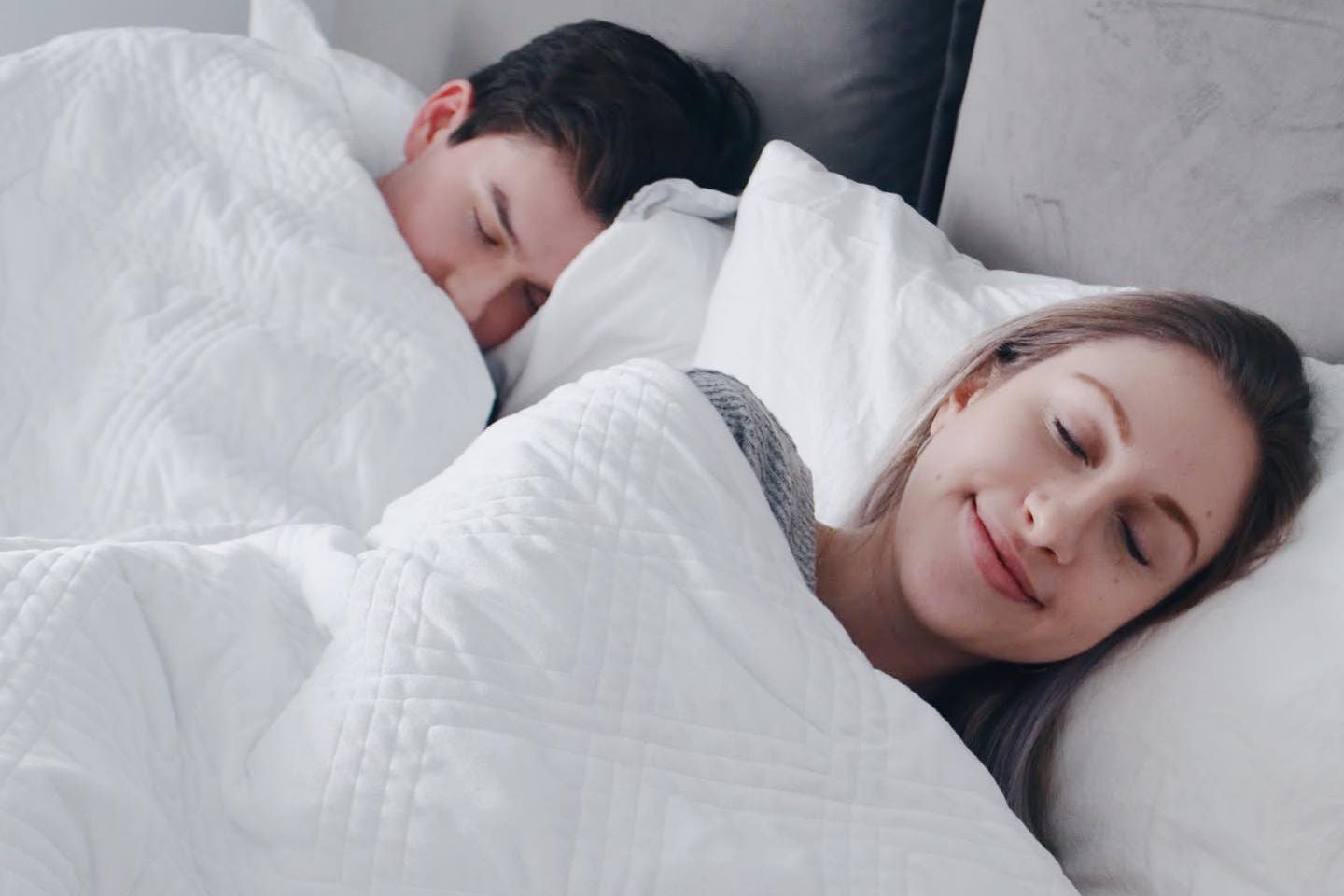 A couple sleeping under a white Hush Classic weighted blanket.