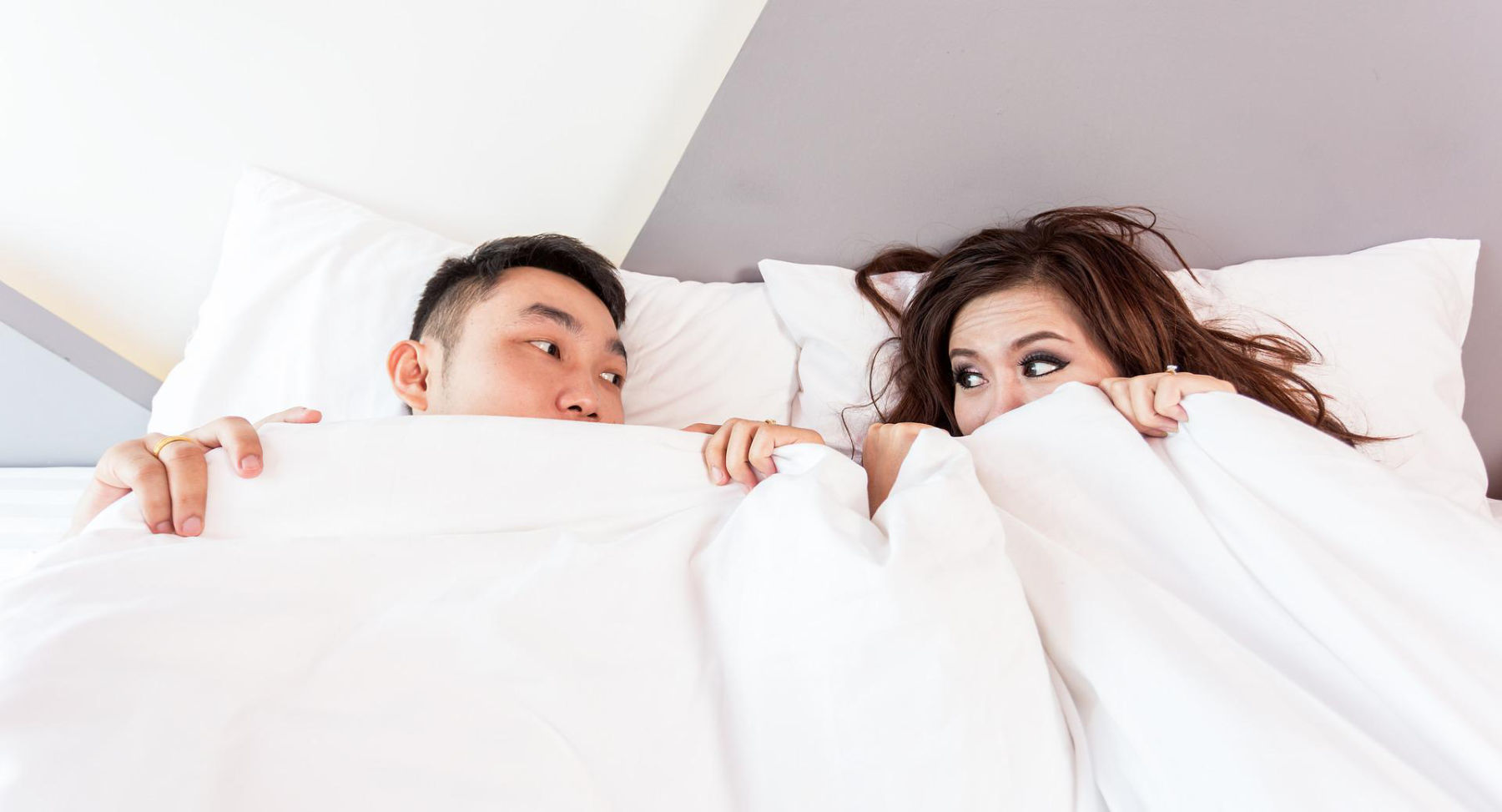 couple covered up with white blanket on bed