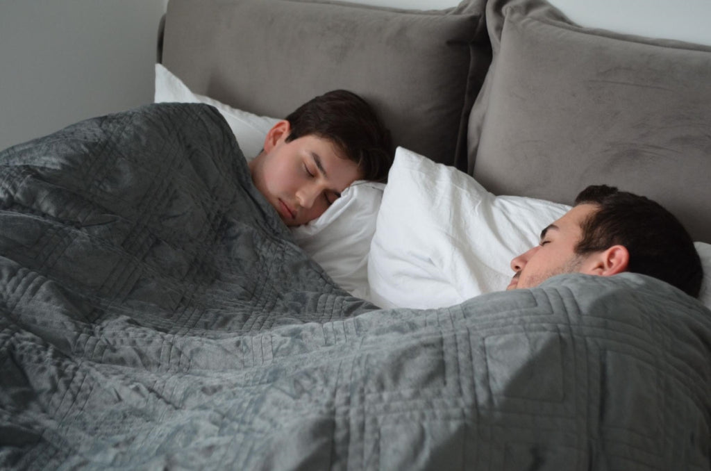 Couple sleeping in bed while covered by a blanket