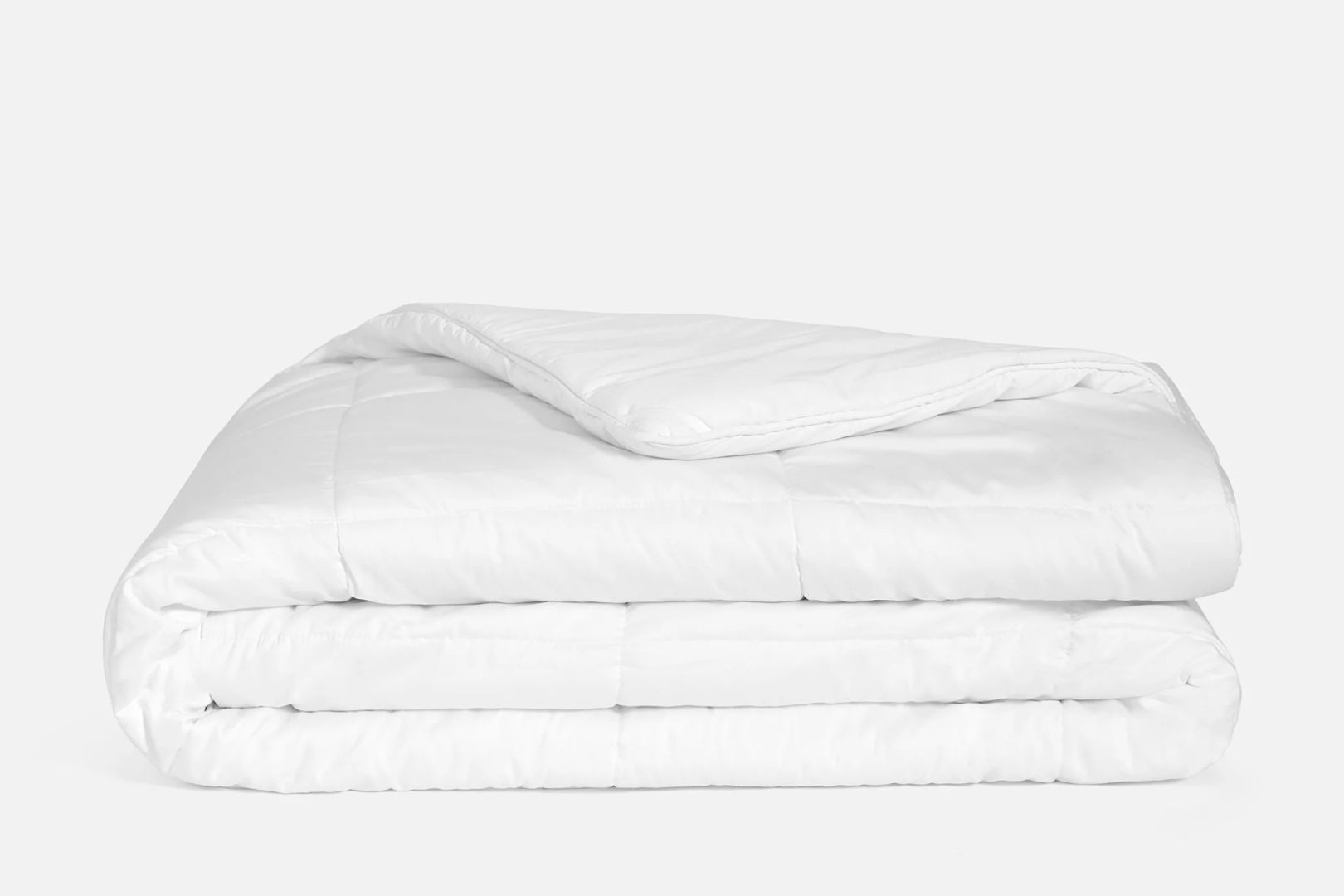 A solid white Brooklinen Weighted Comforter neatly folded on a white surface.