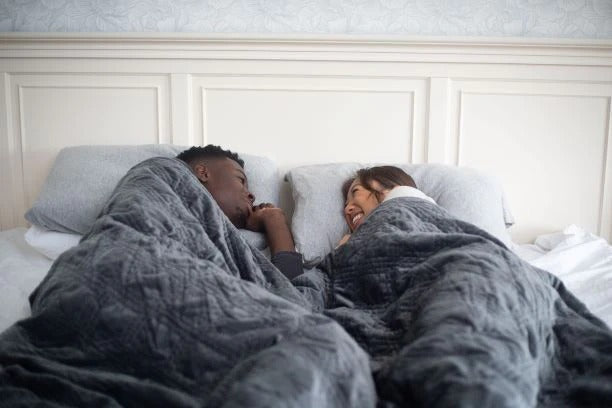 A couple in bed under a Hush Classic Weighted Blanket