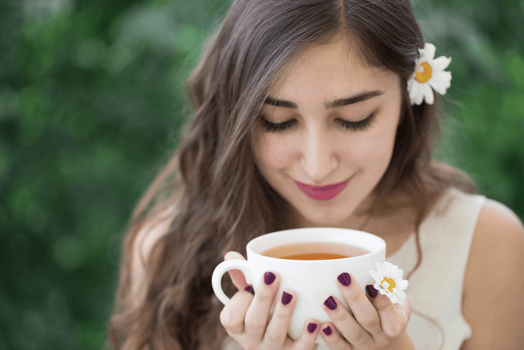 how to fall asleep in 10 seconds:  Smiling woman holding a cup of tea while looking down at it