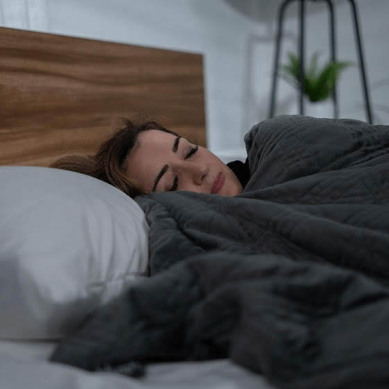 https://cdn.shopify.com/s/files/1/2494/2652/files/woman-sleeping-with-a-weighted-blanket_1024x1024.png?v=1626243024