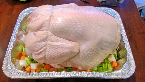 Place the turkey on top of the chopped veggies and tie butchers string around the breast and wings and legs.