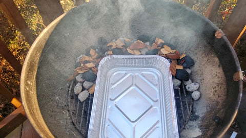 Fill a foil pan with water and place on the bottom grate, surrounded by coals and wood chips. Notice I have already added a few extra new briquettes to the pile.