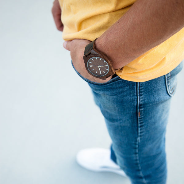 man wearing jeans with yellow shirt and wooden watch on wrist