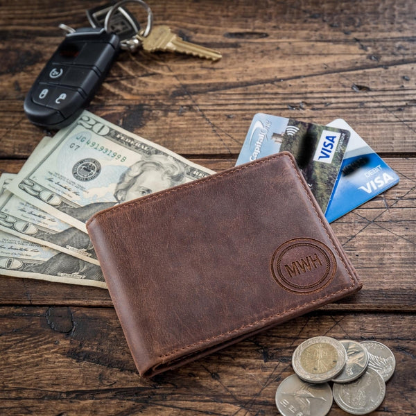 monogramed leather wallet on table with cash credit cards and coins