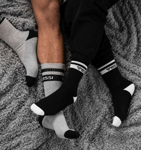 Two people wearing Vessi crew socks on their bed.