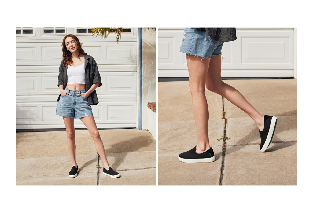 Female wearing Vessi Boardwalk Slip-Ons in Boulder Black with denim cutoffs, white tank top, and open grey button up.