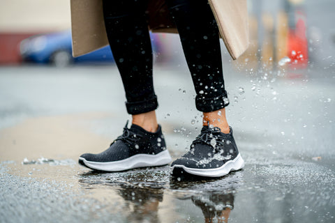 Woman in black Vessi waterproof shoes walking on a wet path