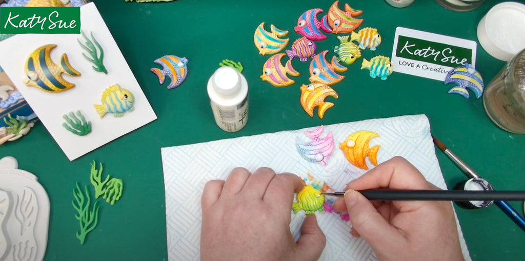 Screen shot from Under the Sea Craft Show showing host painting clay fish