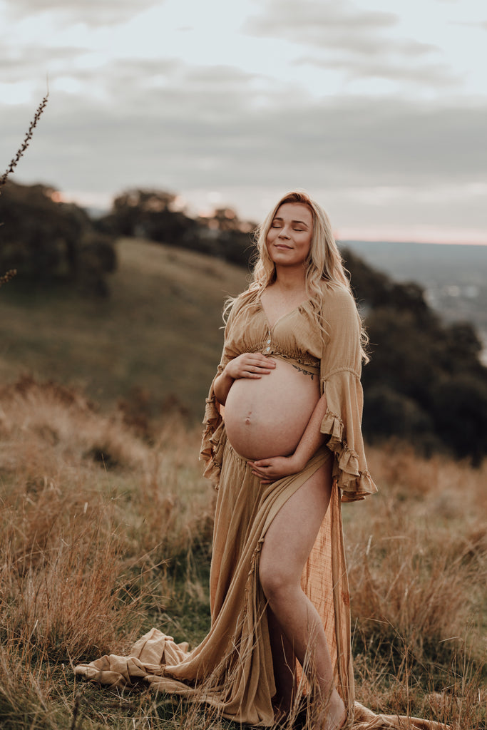 A beautiful pregnant lady wears Mama Rentals Reclamation 'Dreams Like These' three piece gown in Mustard colour at her maternity shoot.