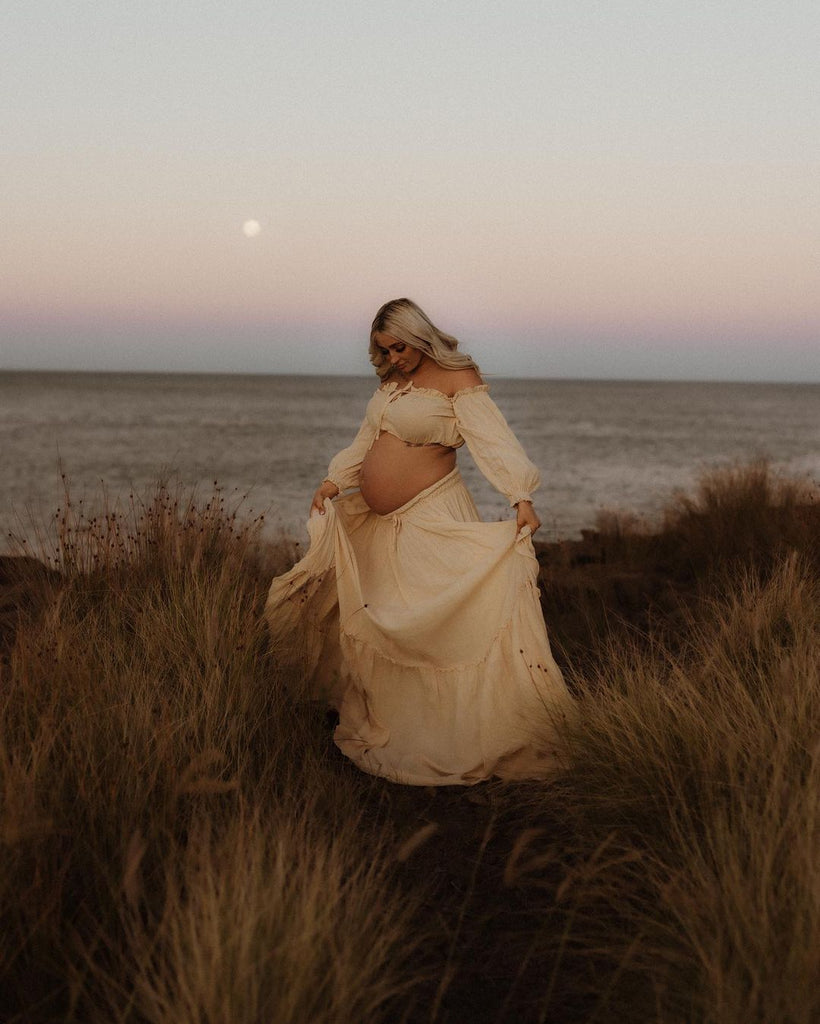 A beautiful pregnant lady wears Reclamation 'There’s Nothing Quite Like You' two piece Gown at her maternity shoot.