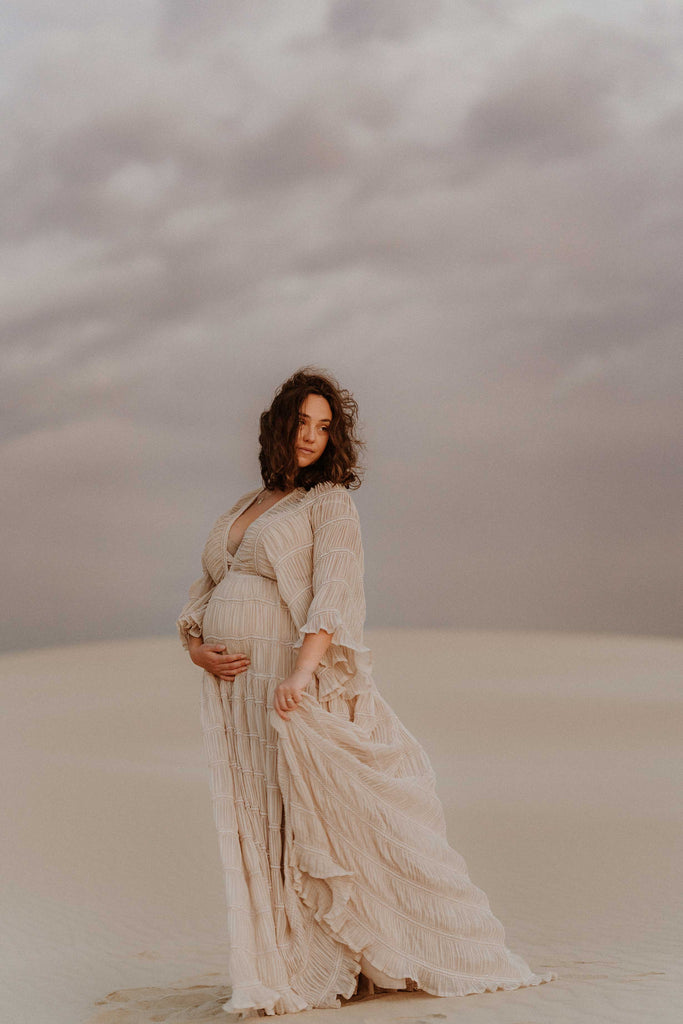 A beautiful pregnant lady wears Mama Rentals' Reclamation Wonderment And Awe Gown at her maternity shoot.