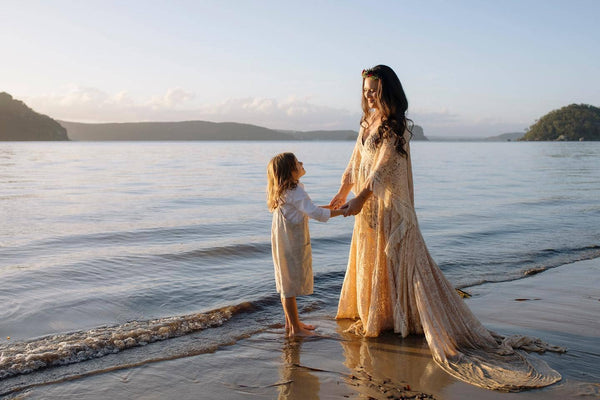Mother and son at a beach family photoshoot, the mum is wearing Mama Rentals' Reclamation Magic Maker Gown in Dark Ivory.