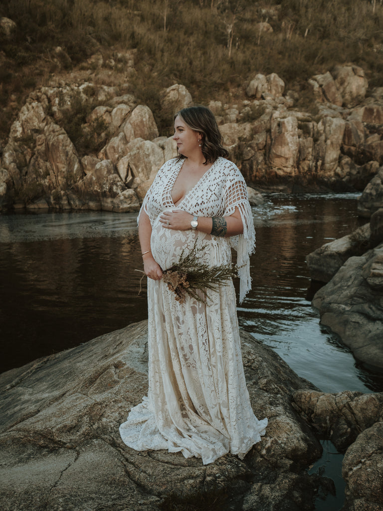 A beautiful pregnant lady wears Mama Rentals' Reclamation 'Bewitched by Boho' gown in Ivory colour at her maternity shoot.
