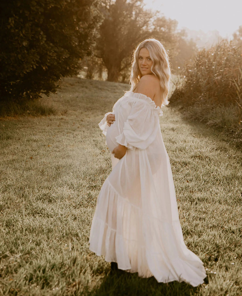 A beautiful pregnant lady wears Hazel and Folk Emmaline Maxi Gown in White at her maternity photo shoot.