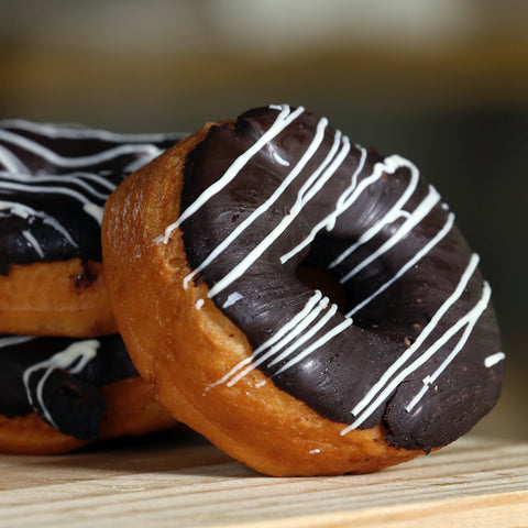 Three chocolate-glazed donuts sitting on a table as an example of dietary contributors to fatigue.