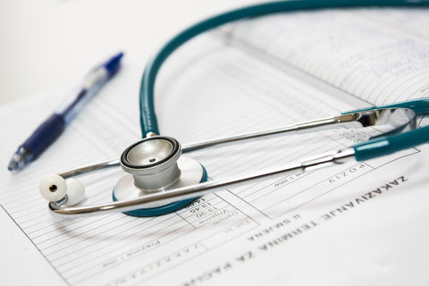 A stethoscope laying on a medical record next to an ink pen. 