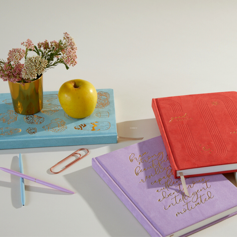 Jumbo journals with apple and flowers sitting on blue journal