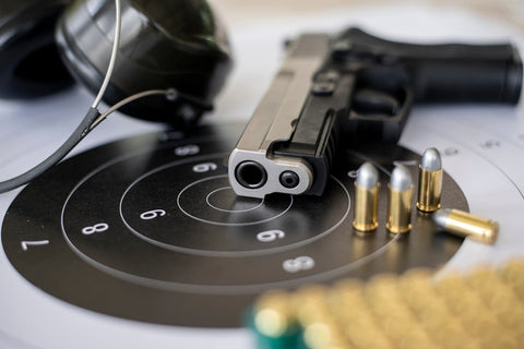 hand gun with bullets on a shooting target